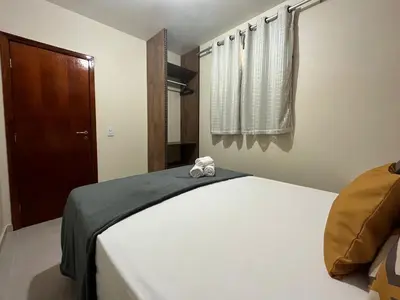 Uma cama ou camas num quarto em TOP 2 QUARTOS em Condominio- PISCINA, CHURRASQUEIRA, ESTACIONAMENTO, PARQUINHO INFANTIL, Wi-Fi e home office, Ar Condicionado, SmarTV e Cozinha Completa I 800m da praia e parque aquatico CE