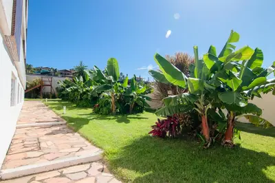 Um jardim no exterior de 2 QUARTOS em CONDOMÍNIO TRANQUILO com PISCINA Estacionamento coberto – PARQUINHO para CRIANCAS - Cozinha Completa, VENTILADO, nascente, AR CONDICIONADO – 800m da praia do PORTO DAS DUNAS e BEACH PARQUE - Ceará
